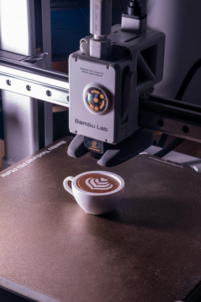 A 3D printer creates intricate latte art in a coffee cup, showcasing technological innovation in food preparation.